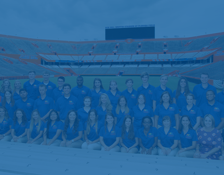 Blue filter over a photo of Florida Youth Institute participants and counselors pose wearing blue polos at the UF Ben Hill Griffith stadium.