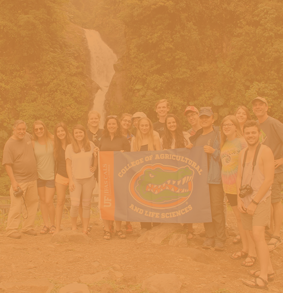 CALS students studying abroad in Costa Rica, posing with a UF flag in front of a waterfall 
