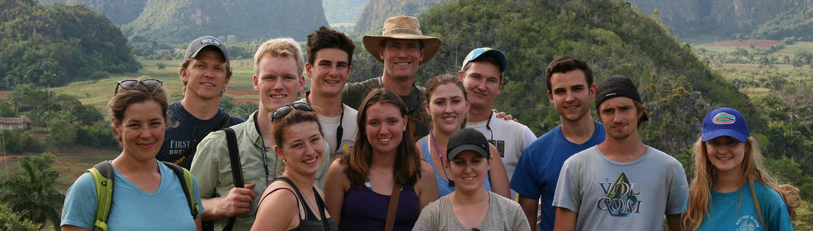 Thirteen UF students studying abroad in Cuba pose for a picture in front of Cuba's tropical ecological landscape.