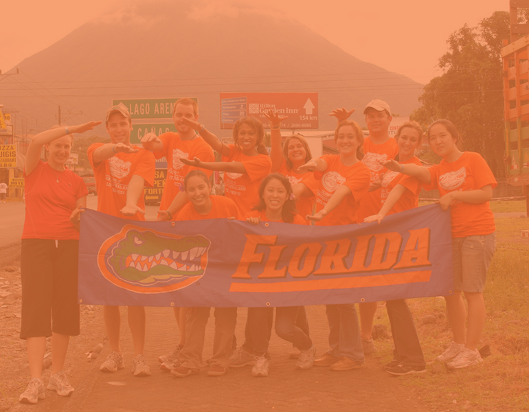 CALS students studying abroad in Peru pose for a photo with a mountainin the background, wearing matching orange gator shirts and gator chomping. 