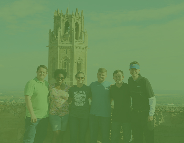 Six CALS students studying abroad in Spain posing for a picture on a city overlook with a tower int he background. 