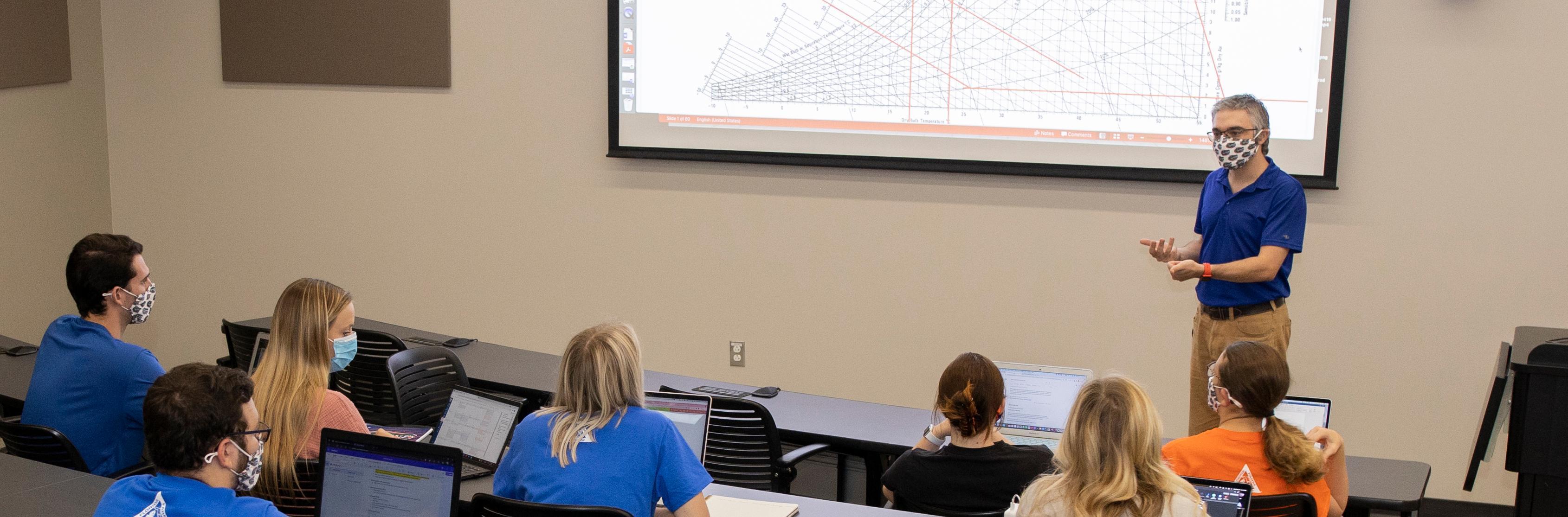 A professor delivers a lecture to students in a classroom. 