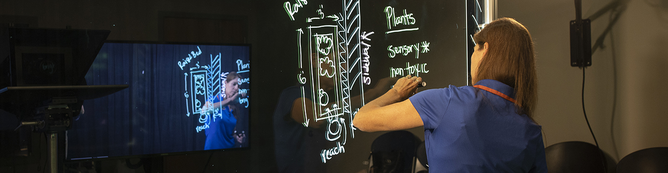 An instructor writing on a lightboard