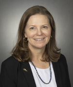 Portrait photo of a woman wearing a white shirt and black blazer with a gator pin on her lapel.