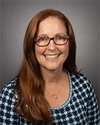 Studio portrait of a woman wearing glasses and wearing a checked shirt.