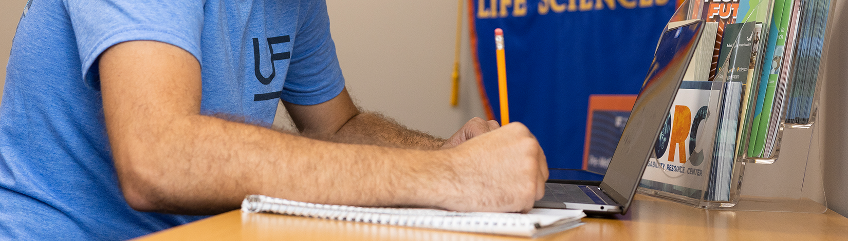 Student writes in a notebook with a pencil.