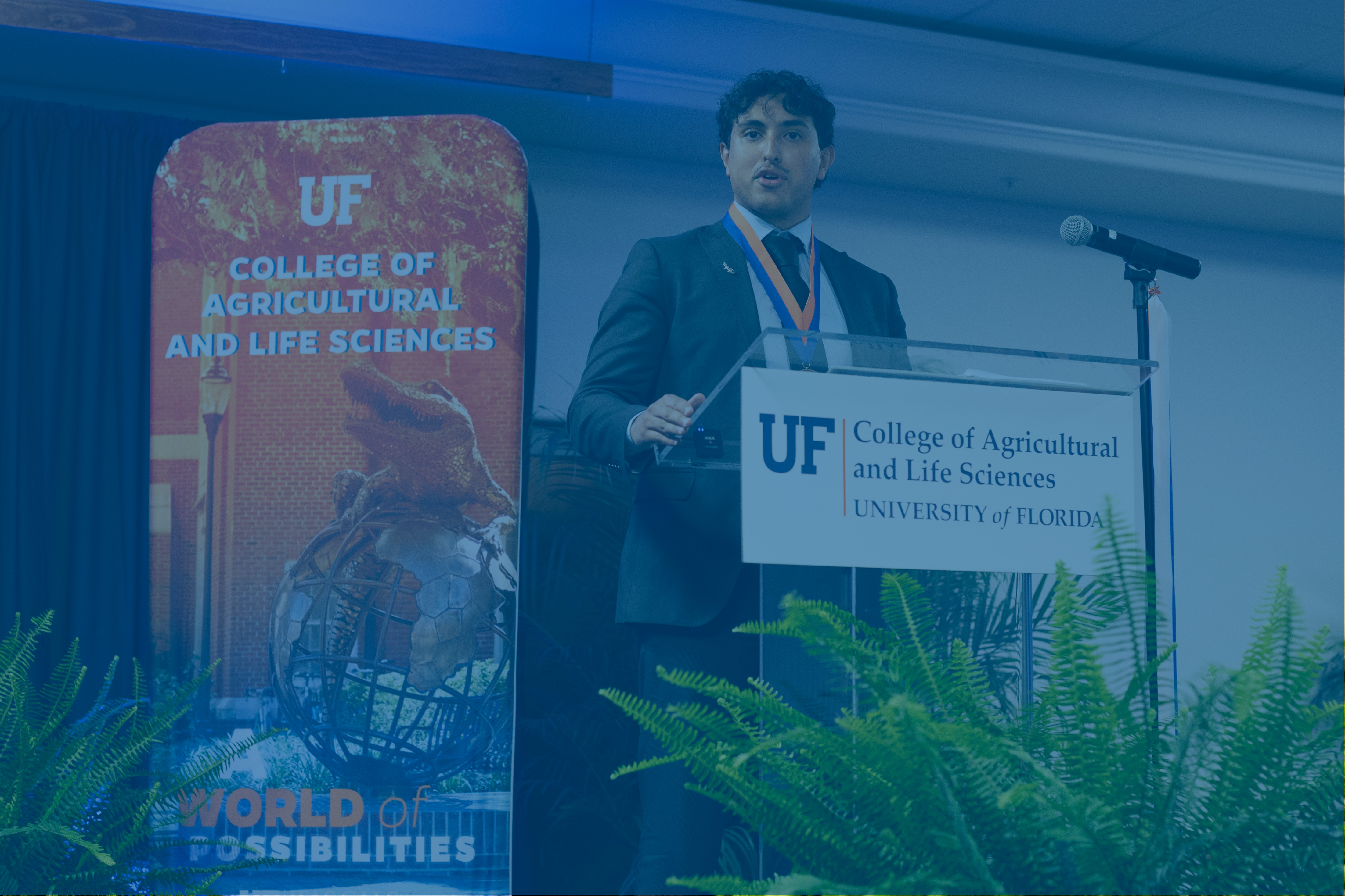 Student standing at a podium hosting a dinner.