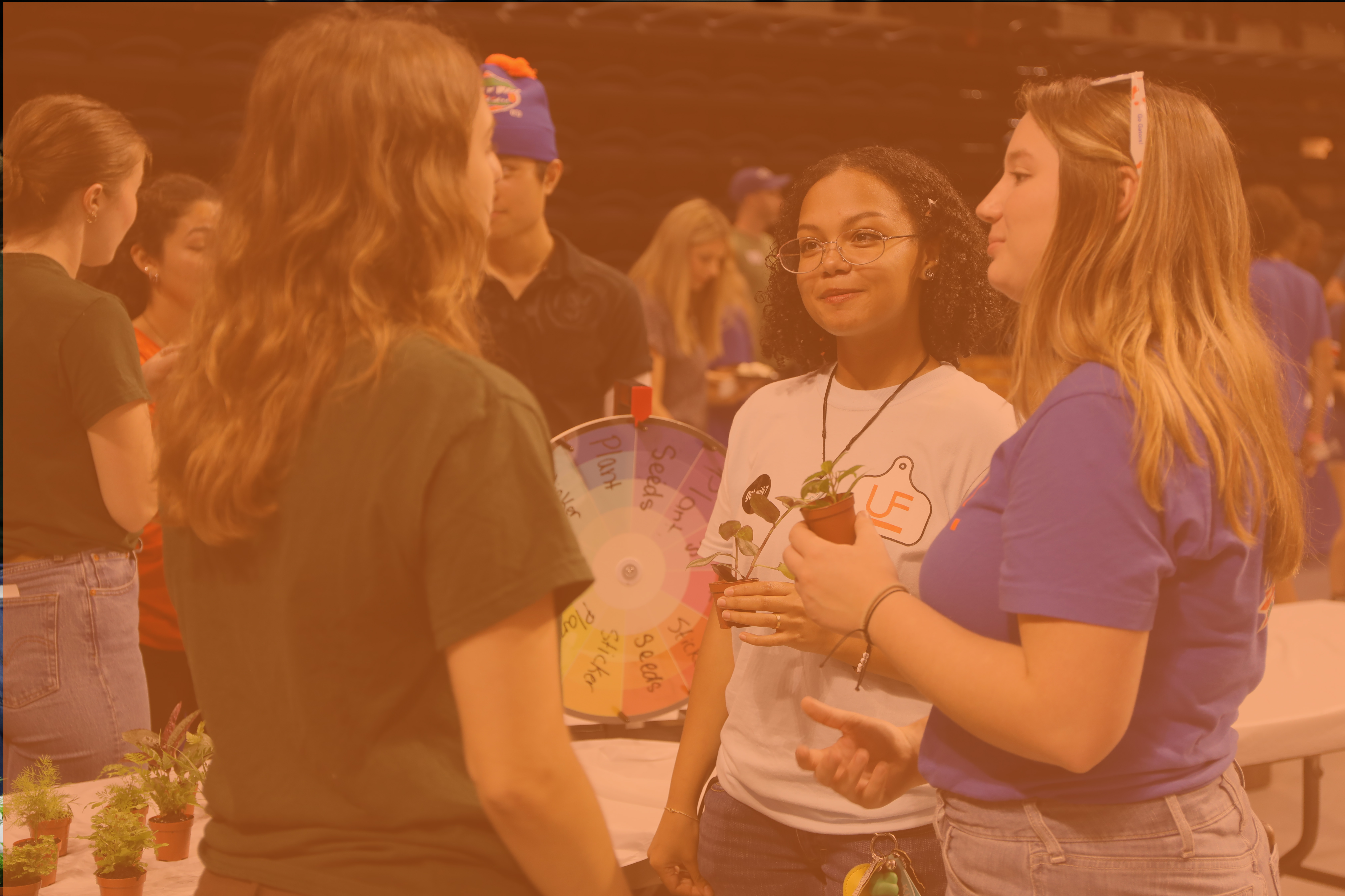 students in green and blue shirts standing at a tailgate event.