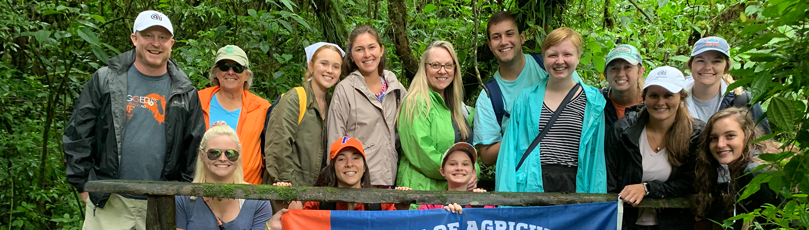 Students and faculty member stand on a bridge in a tropical rainforest for a picture.