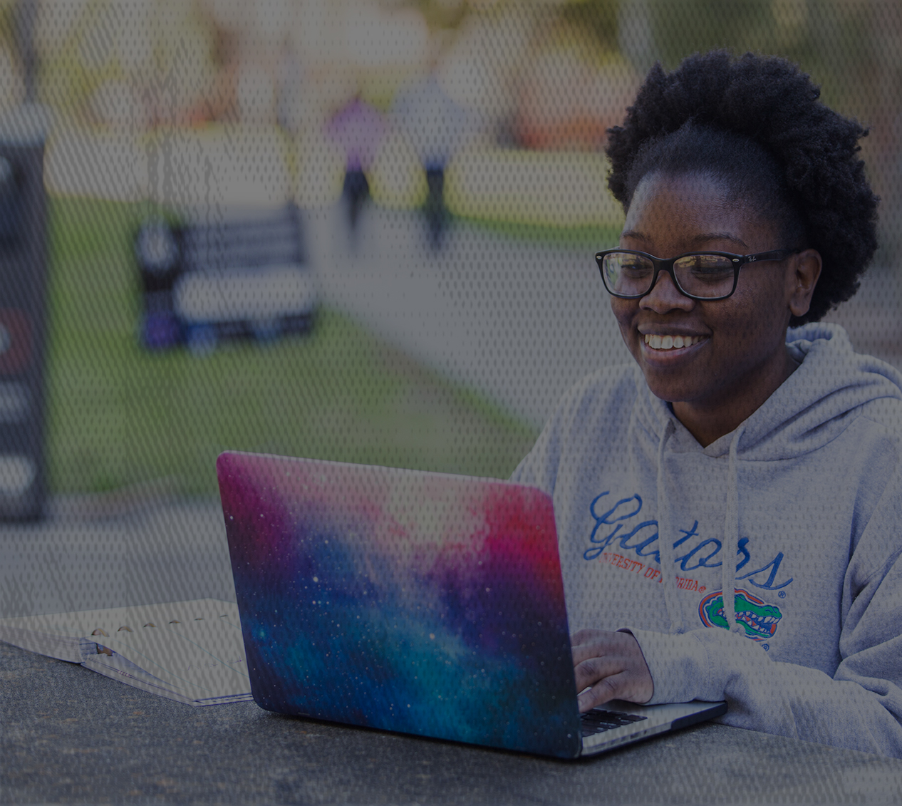 CALS distance education student sitting on a bench with her multicolored laptop. 