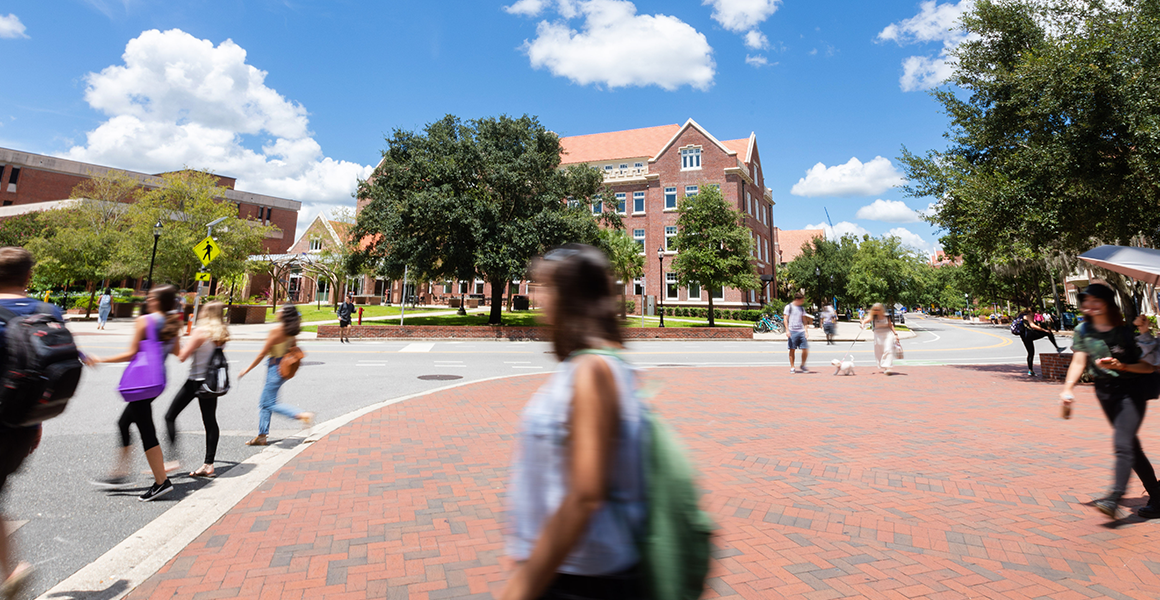 Students wearing backpacks move in a blurred path across a brick path.